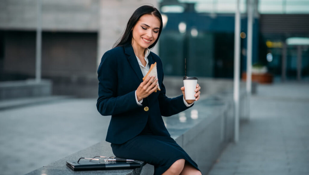 Co na śniadanie do pracy zamiast kanapek? 5 pomysłów kobieta jedząca śniadanie przed biurem
