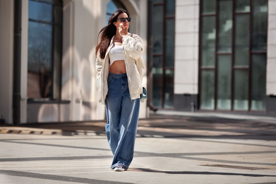 Stylizacja damska: biały top, kremowa kurtka, szerokie jeansy i trampki
